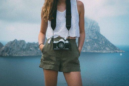 Woman with a camera standing in front of a lake